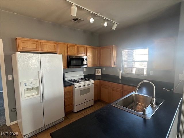 kitchen with dark countertops, visible vents, light tile patterned floors, white appliances, and a sink