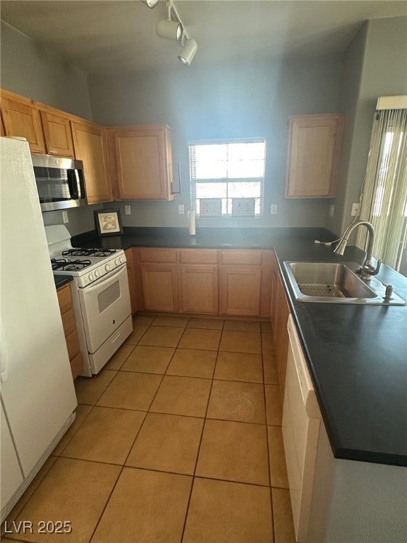 kitchen featuring light brown cabinetry, a sink, white appliances, a peninsula, and light tile patterned floors