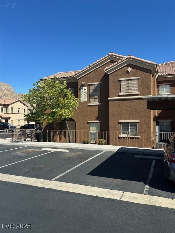 view of building exterior with uncovered parking and fence