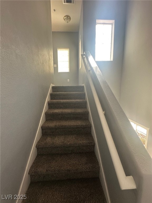 stairs with visible vents, baseboards, and a textured wall