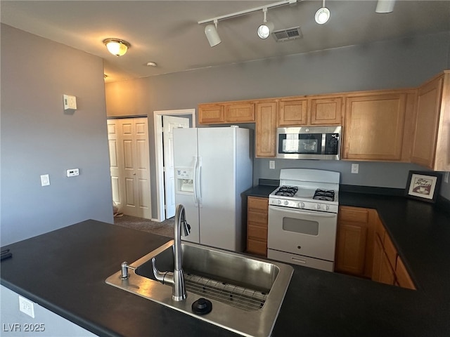 kitchen with a sink, visible vents, white appliances, and dark countertops