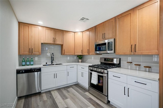 kitchen featuring a sink, stainless steel appliances, visible vents, and light countertops