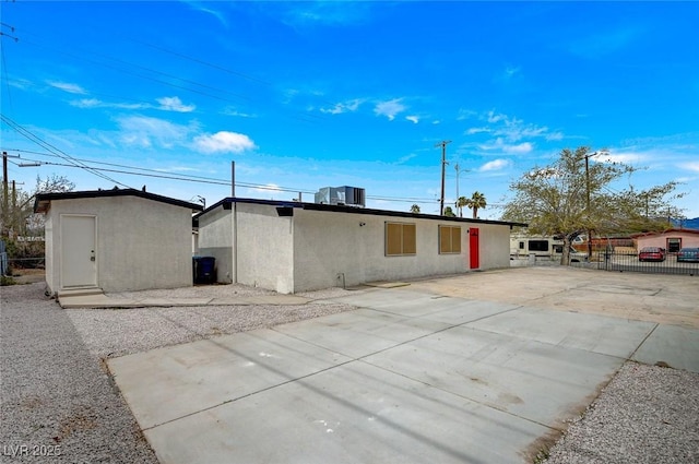 rear view of property featuring stucco siding, a patio area, and fence