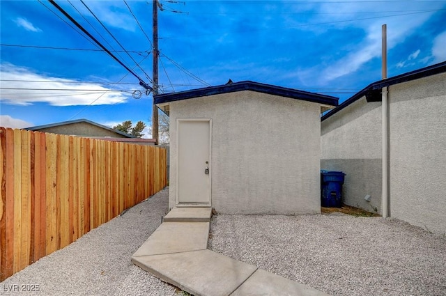 view of exterior entry featuring a patio, fence, and stucco siding