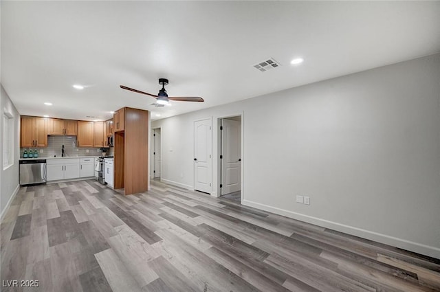 unfurnished living room featuring baseboards, visible vents, ceiling fan, a sink, and light wood-style floors