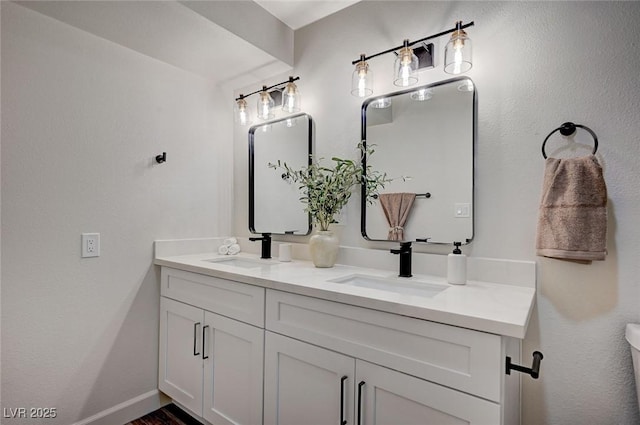 bathroom featuring double vanity, baseboards, and a sink