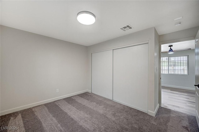 unfurnished bedroom with a closet, carpet flooring, visible vents, and baseboards