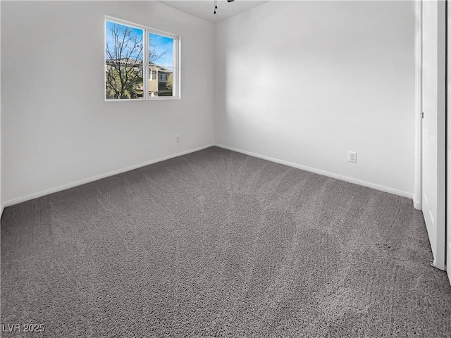 unfurnished room with baseboards, dark carpet, and ceiling fan