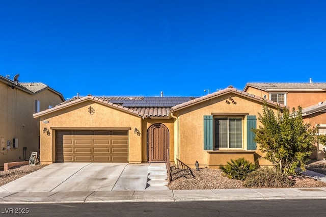 mediterranean / spanish house featuring stucco siding, roof mounted solar panels, concrete driveway, a garage, and a tiled roof