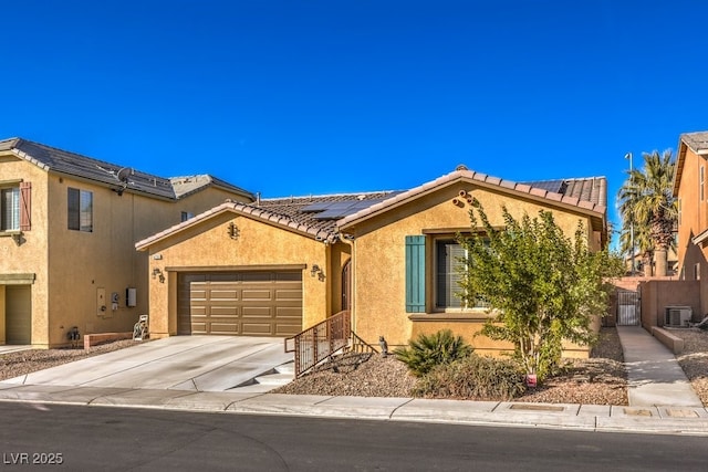 mediterranean / spanish home featuring a garage, roof mounted solar panels, stucco siding, and a gate