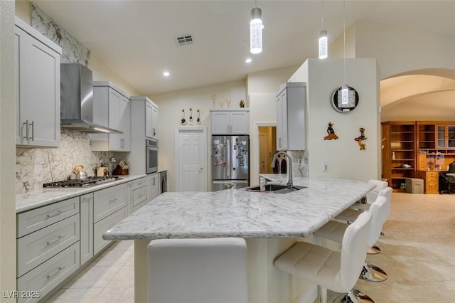 kitchen with gray cabinets, a sink, stainless steel appliances, a peninsula, and wall chimney range hood