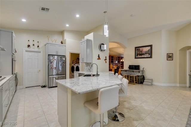 kitchen with arched walkways, independent washer and dryer, a peninsula, and freestanding refrigerator