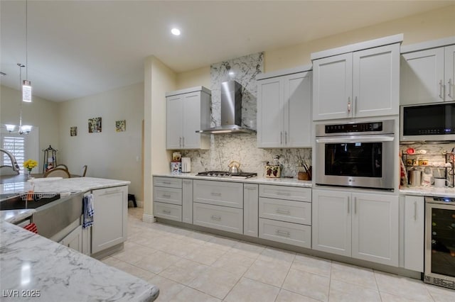 kitchen with beverage cooler, a sink, stainless steel appliances, wall chimney range hood, and decorative backsplash