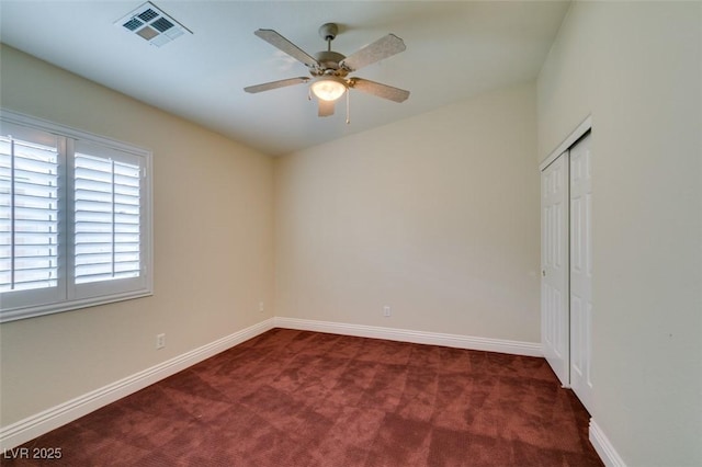 carpeted spare room with visible vents, baseboards, and ceiling fan