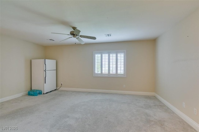 empty room featuring baseboards, light colored carpet, visible vents, and ceiling fan