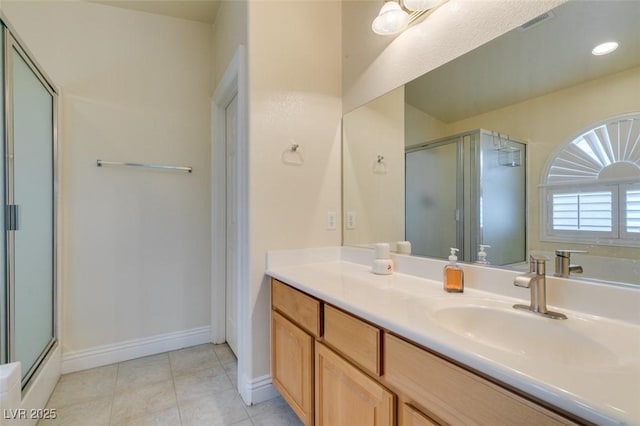 full bath featuring a shower with door, tile patterned floors, vanity, and baseboards