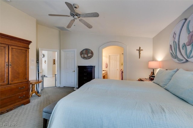 bedroom with visible vents, ensuite bath, arched walkways, dark colored carpet, and lofted ceiling