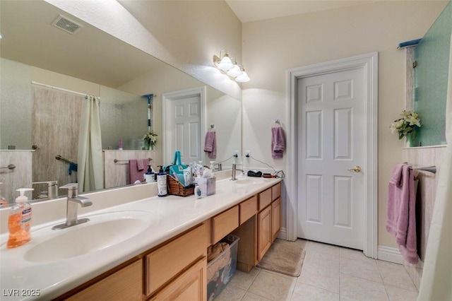 full bath with a sink, visible vents, double vanity, and tile patterned flooring