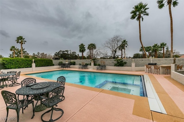 view of pool with a patio, fence, a pool with connected hot tub, and outdoor dry bar