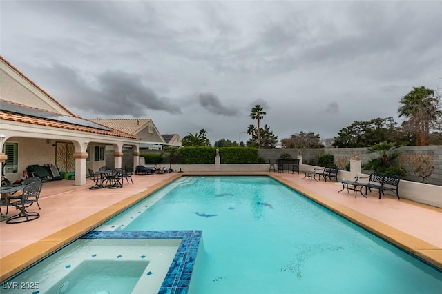 view of swimming pool featuring a patio area, a pool with connected hot tub, and fence