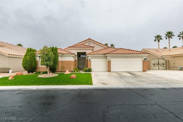 mediterranean / spanish house with a gate, an attached garage, stucco siding, concrete driveway, and a tile roof