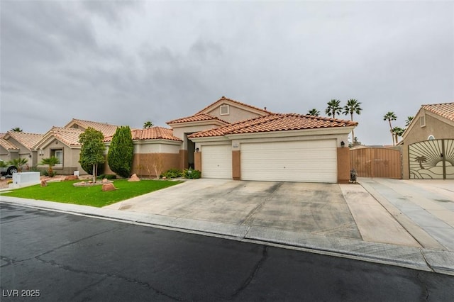 mediterranean / spanish house with driveway, a gate, a front yard, an attached garage, and a tiled roof