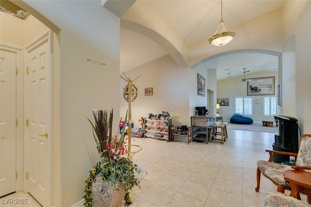 entrance foyer featuring lofted ceiling, light tile patterned flooring, and arched walkways