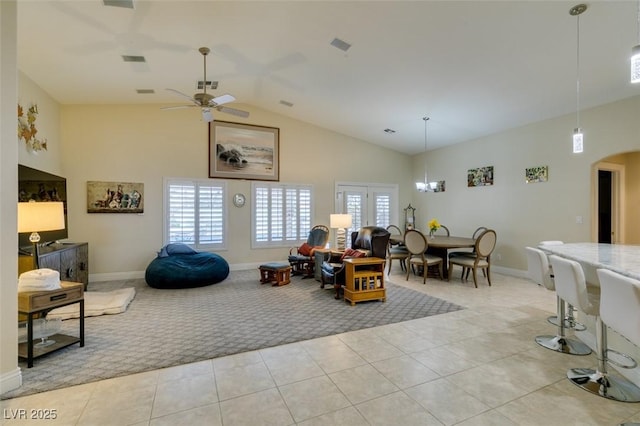 living room featuring visible vents, light tile patterned floors, ceiling fan with notable chandelier, arched walkways, and high vaulted ceiling