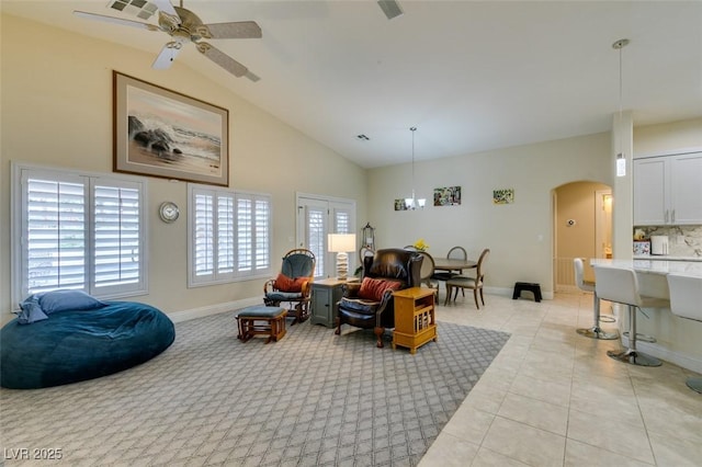 living area featuring light tile patterned floors, a ceiling fan, baseboards, arched walkways, and vaulted ceiling