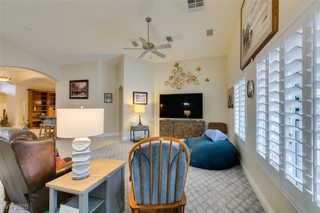 carpeted living room with baseboards, arched walkways, visible vents, and ceiling fan