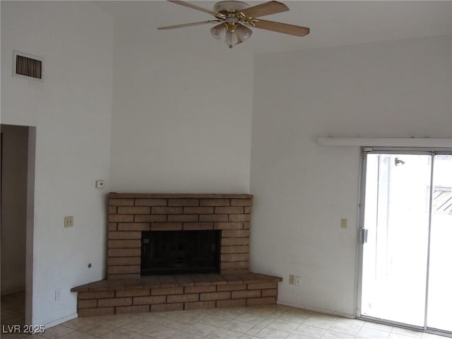 unfurnished living room with visible vents, a brick fireplace, and ceiling fan