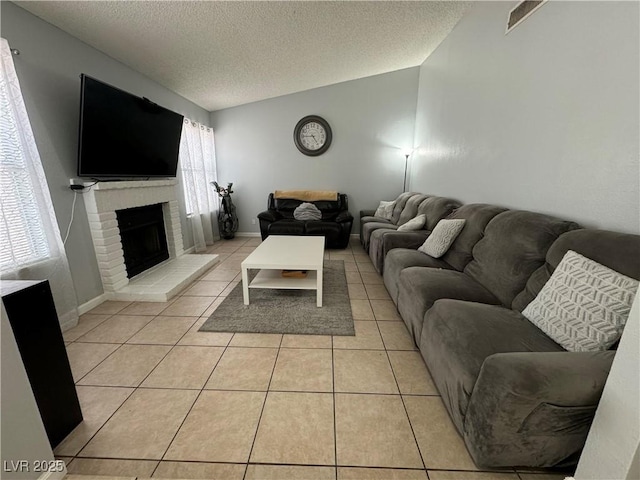 living area featuring baseboards, light tile patterned flooring, a fireplace, vaulted ceiling, and a textured ceiling