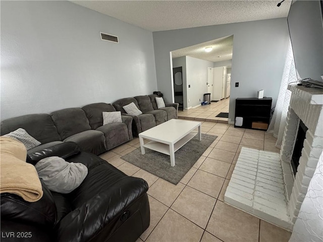 living area with light tile patterned floors, visible vents, a textured ceiling, and a fireplace