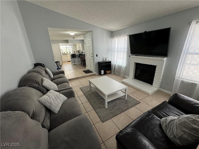 living room with lofted ceiling, a textured ceiling, light tile patterned floors, baseboards, and a brick fireplace