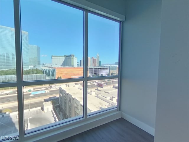 empty room with a view of city, baseboards, and wood finished floors