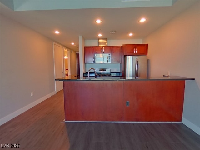 kitchen with brown cabinetry, baseboards, dark wood-style flooring, appliances with stainless steel finishes, and dark countertops