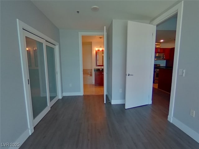 interior space featuring baseboards, a notable chandelier, dark wood finished floors, and ensuite bathroom