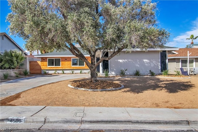 ranch-style house featuring fence and stucco siding