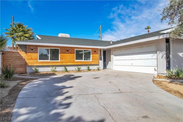 single story home with a shingled roof, a garage, driveway, and stucco siding