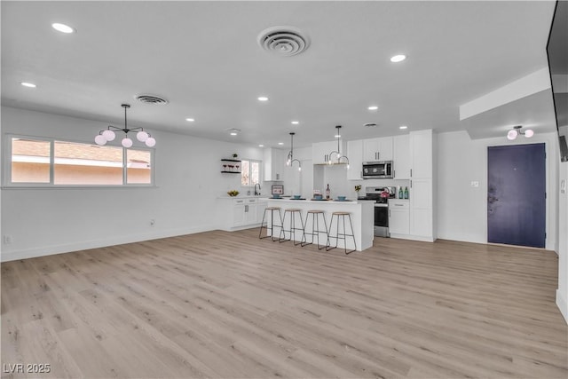 kitchen featuring stainless steel appliances, visible vents, white cabinets, and light wood-style flooring