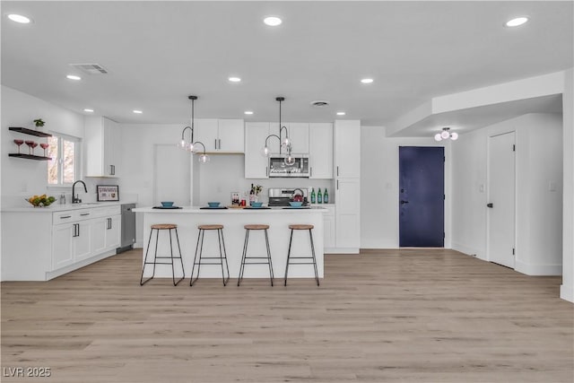 kitchen featuring open shelves, stainless steel appliances, light countertops, light wood-style floors, and white cabinetry