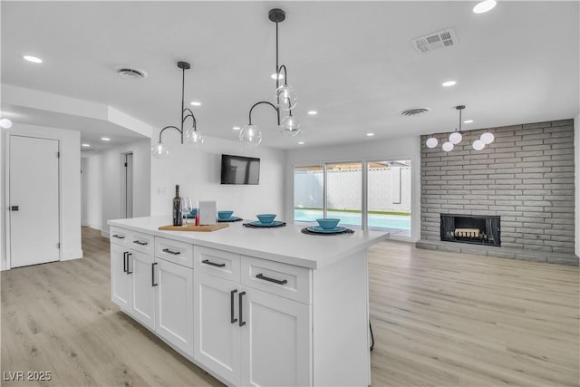 kitchen featuring light wood finished floors, visible vents, white cabinets, and open floor plan