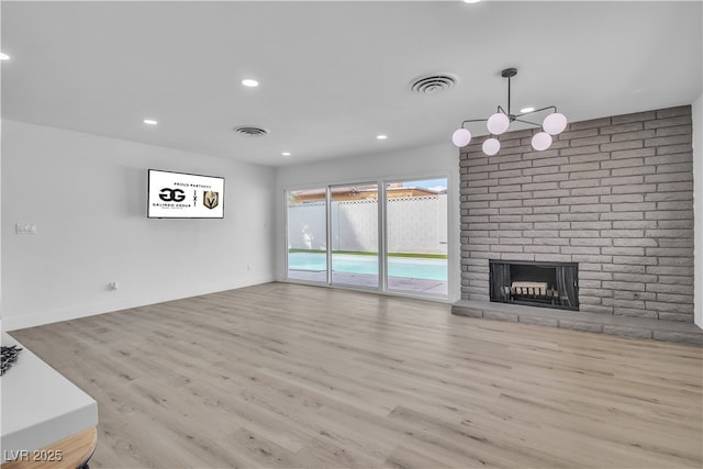 unfurnished living room featuring a fireplace, recessed lighting, wood finished floors, and visible vents