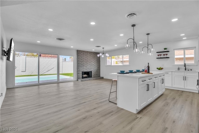 kitchen with light wood finished floors, visible vents, and white cabinetry