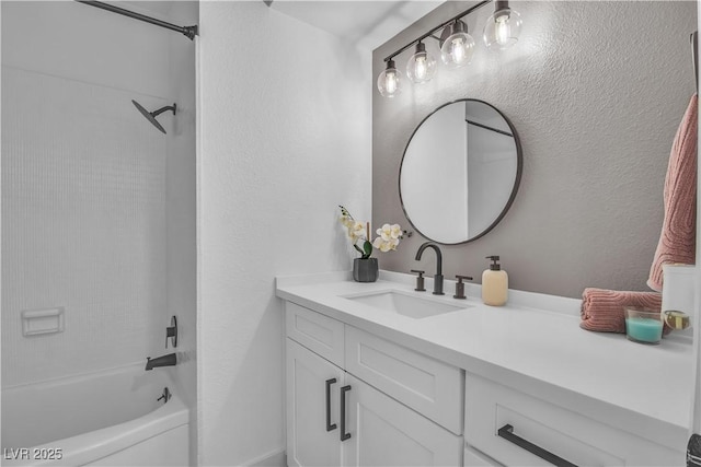 full bath with shower / bathtub combination, vanity, and a textured wall