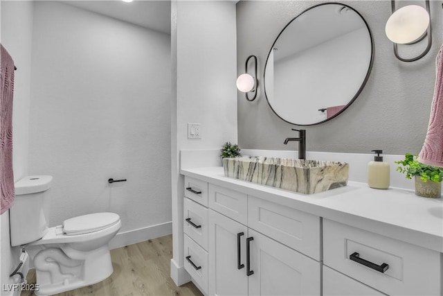 bathroom featuring vanity, toilet, wood finished floors, and baseboards