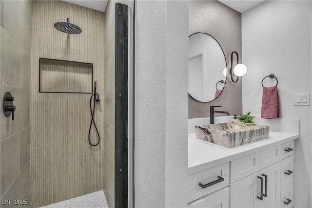 bathroom with vanity and a tile shower