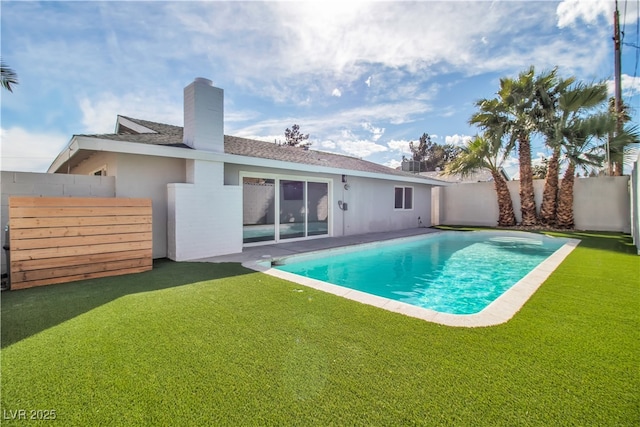 rear view of house featuring a lawn, a chimney, a fenced backyard, and a fenced in pool