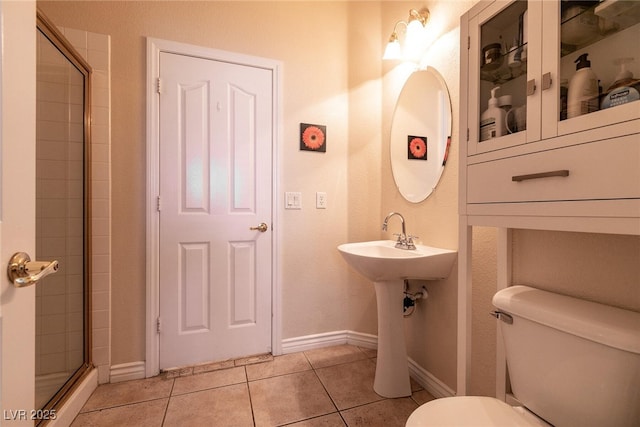 full bath with tile patterned floors, toilet, baseboards, and tiled shower