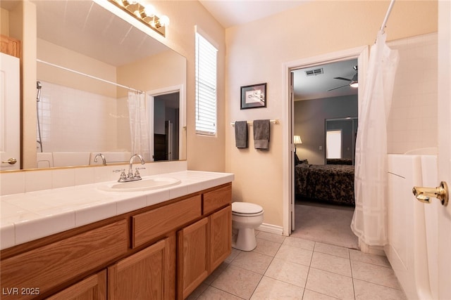 ensuite bathroom with visible vents, ceiling fan, toilet, tile patterned floors, and vanity